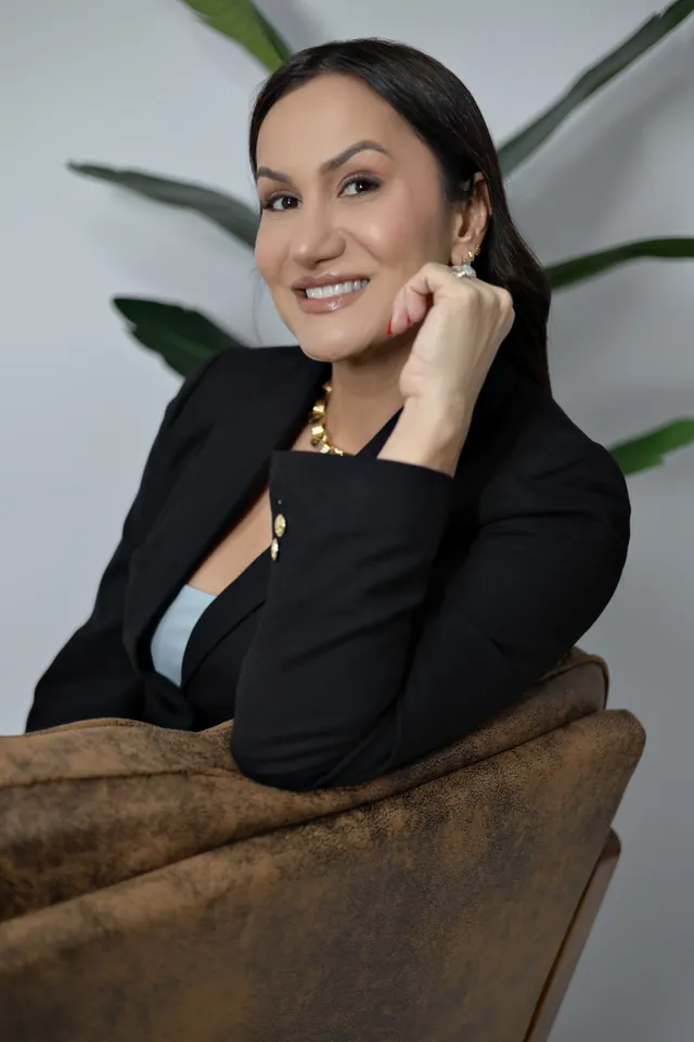 Portrait of Bianca in a black blazer, leaning on an armchair with her chin on her hand